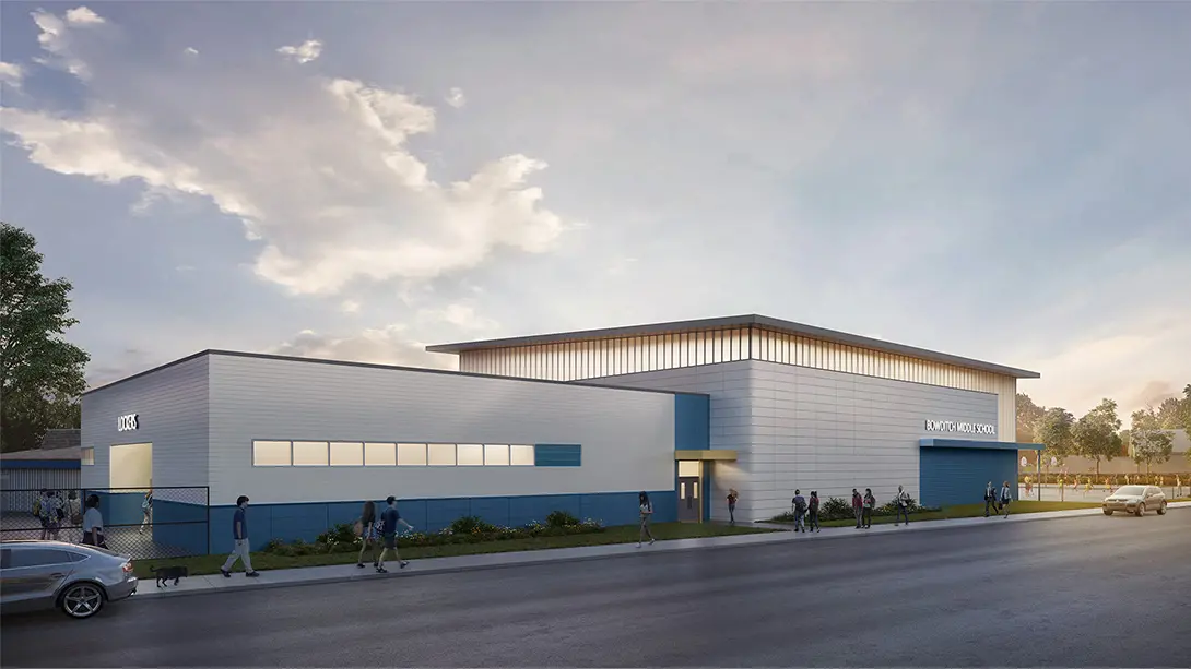 Modern middle school building under a cloudy sky with students walking outside at dusk.