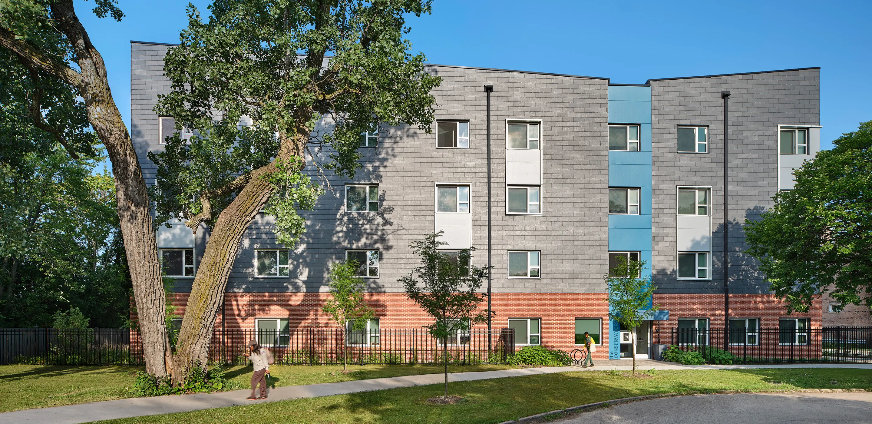 Modern apartment building with trees on a sunny day, showcasing urban living and architecture.