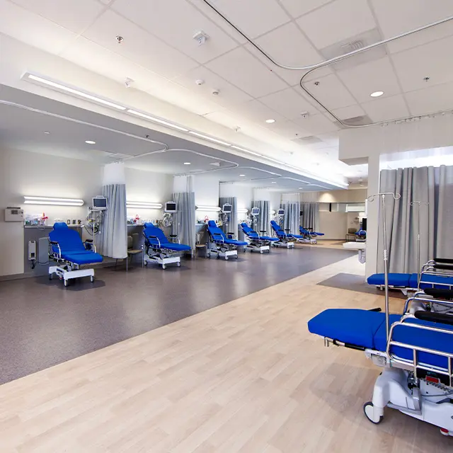 Modern hospital room with multiple blue medical chairs, privacy curtains, and equipment, ready for patients.
