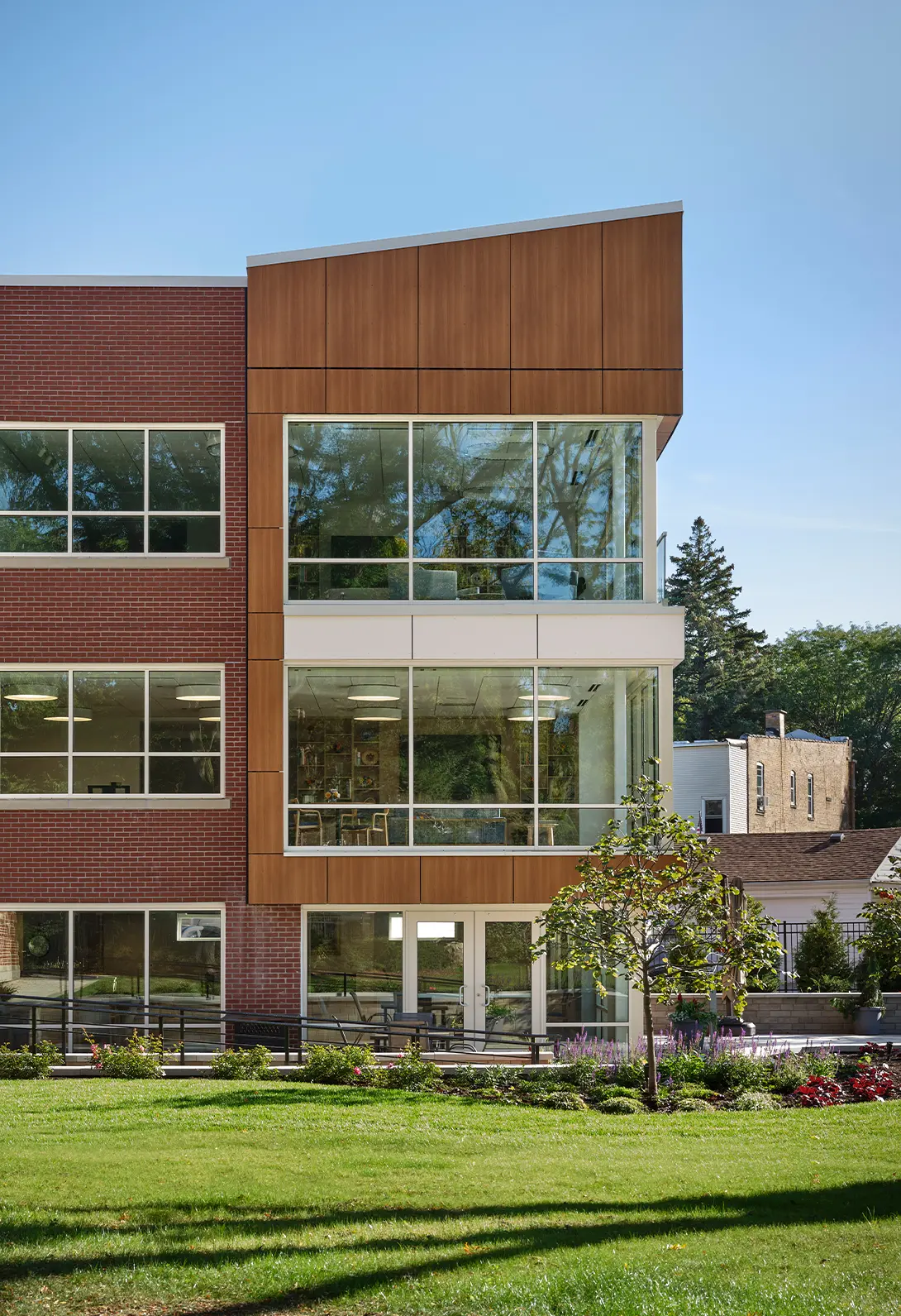 Modern brick and glass office building with green landscaping and a clear blue sky.