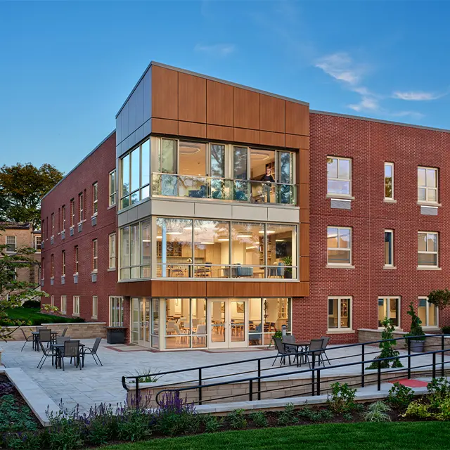 Modern brick building with large glass windows and outdoor seating, showcasing architectural design.