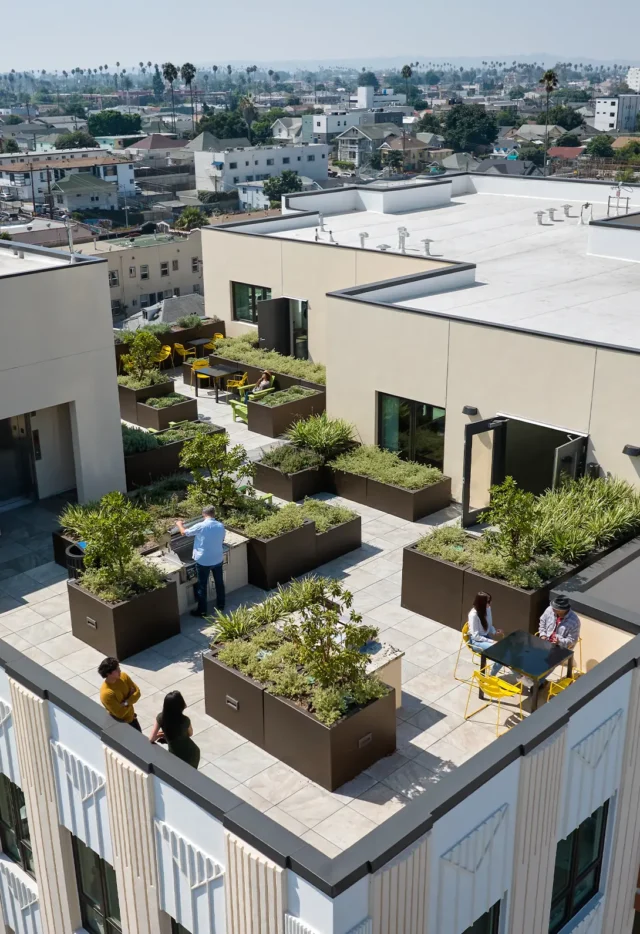 Rooftop garden with people enjoying outdoor seating, surrounded by cityscape views under a clear sky.