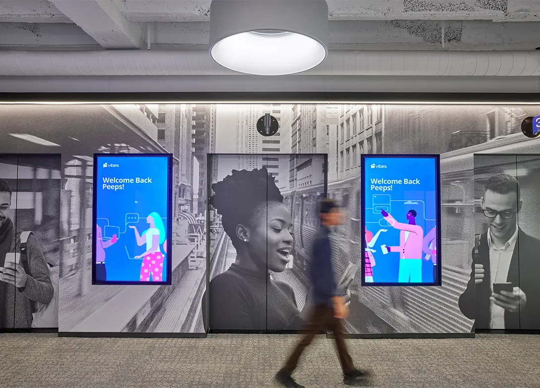 Modern office lobby with digital screens displaying Welcome Back Peeps and artistic black-and-white wall graphics.