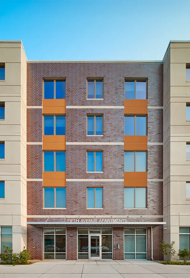 Modern apartment building with brick facade and large windows, named Fifti Avenue Apartments.