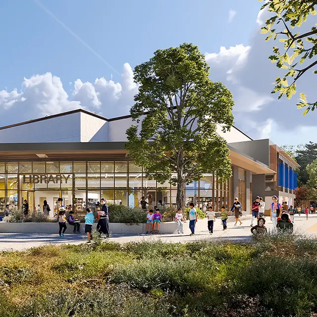 Modern library exterior with people enjoying the sunny day, featuring large windows and surrounding greenery.