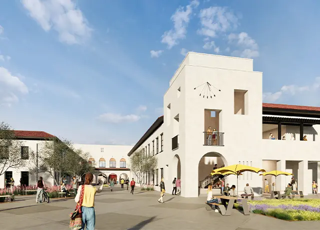 Sunny Mediterranean-style architecture with people walking and relaxing in a courtyard under umbrellas.