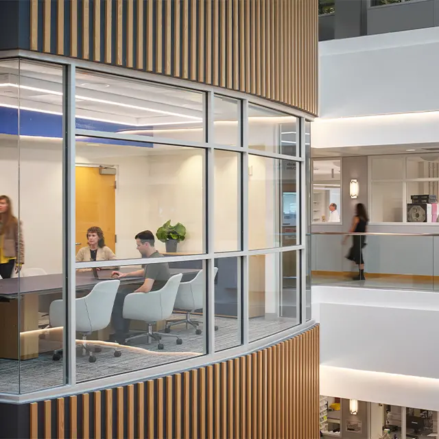 Modern office meeting room with glass walls, featuring a group discussion.