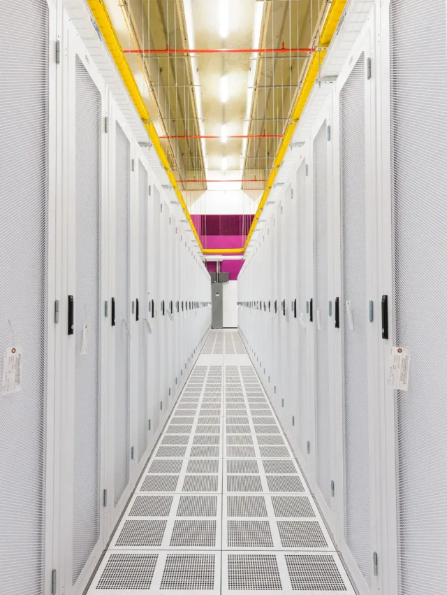 Modern data center aisle with server racks and bright overhead lighting.