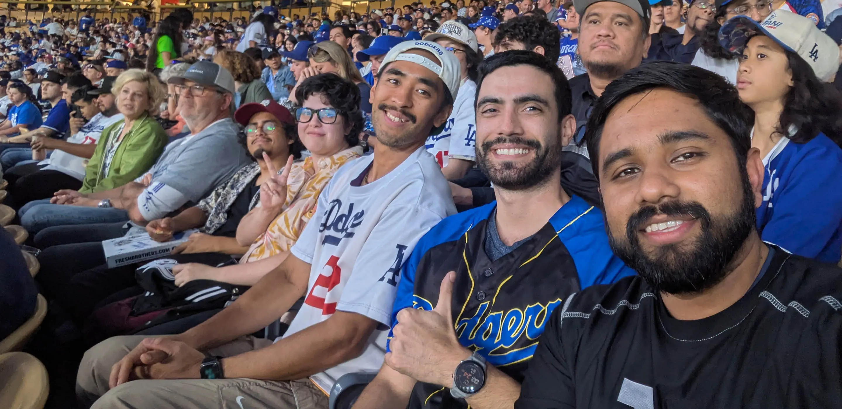 Group of friends enjoying a baseball game at a crowded stadium, smiling and wearing team jerseys.