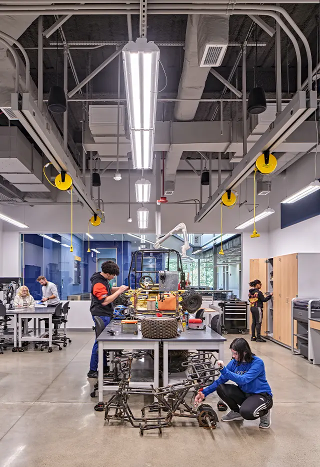 Innovative workshop with students building and assembling machinery at workstation in tech lab.