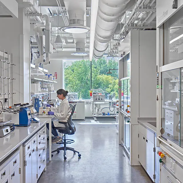 Scientist working in a modern laboratory with advanced equipment and bright natural lighting.