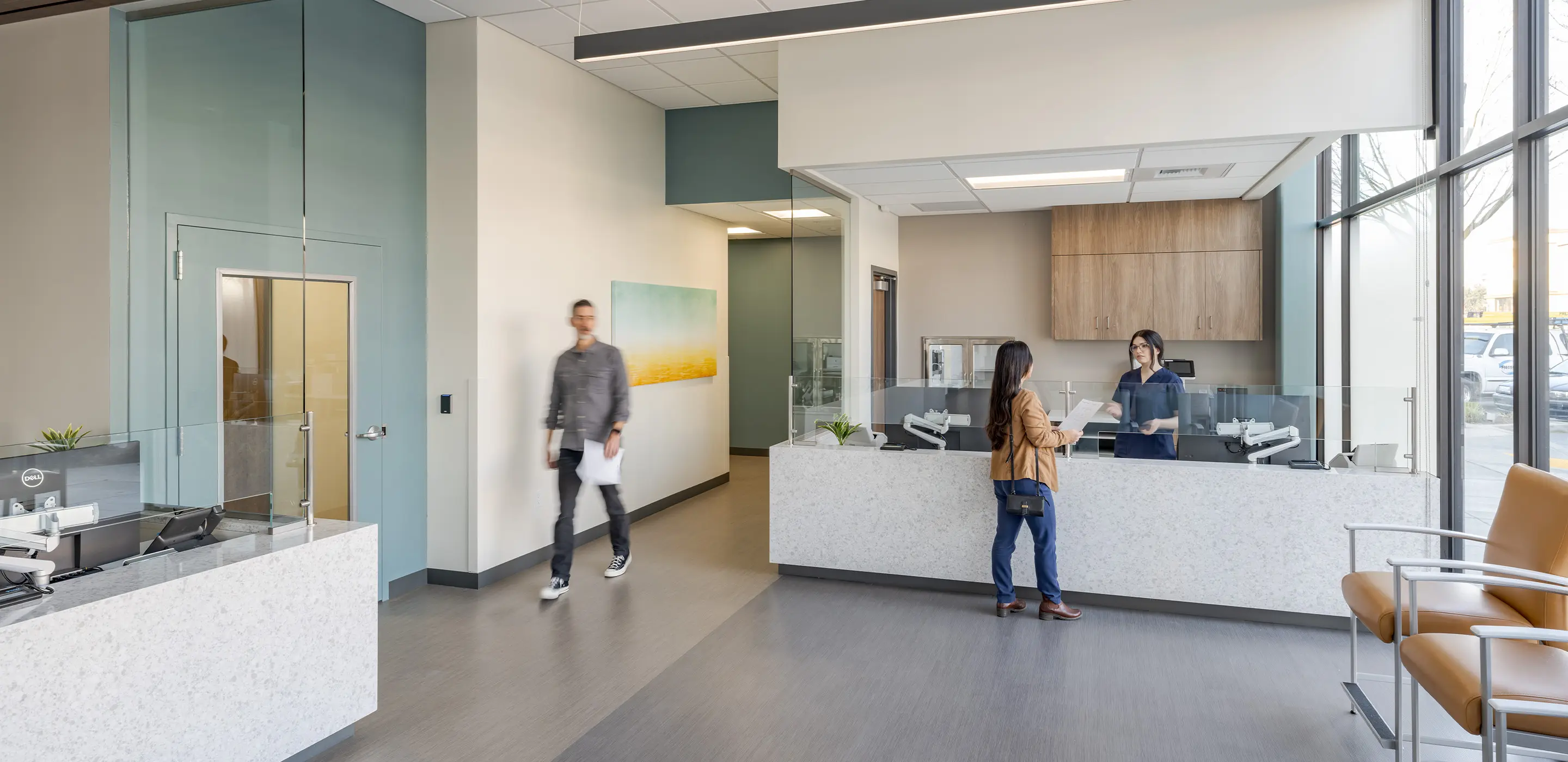 Modern dental office reception area with a patient interacting with the receptionist, featuring sleek design.