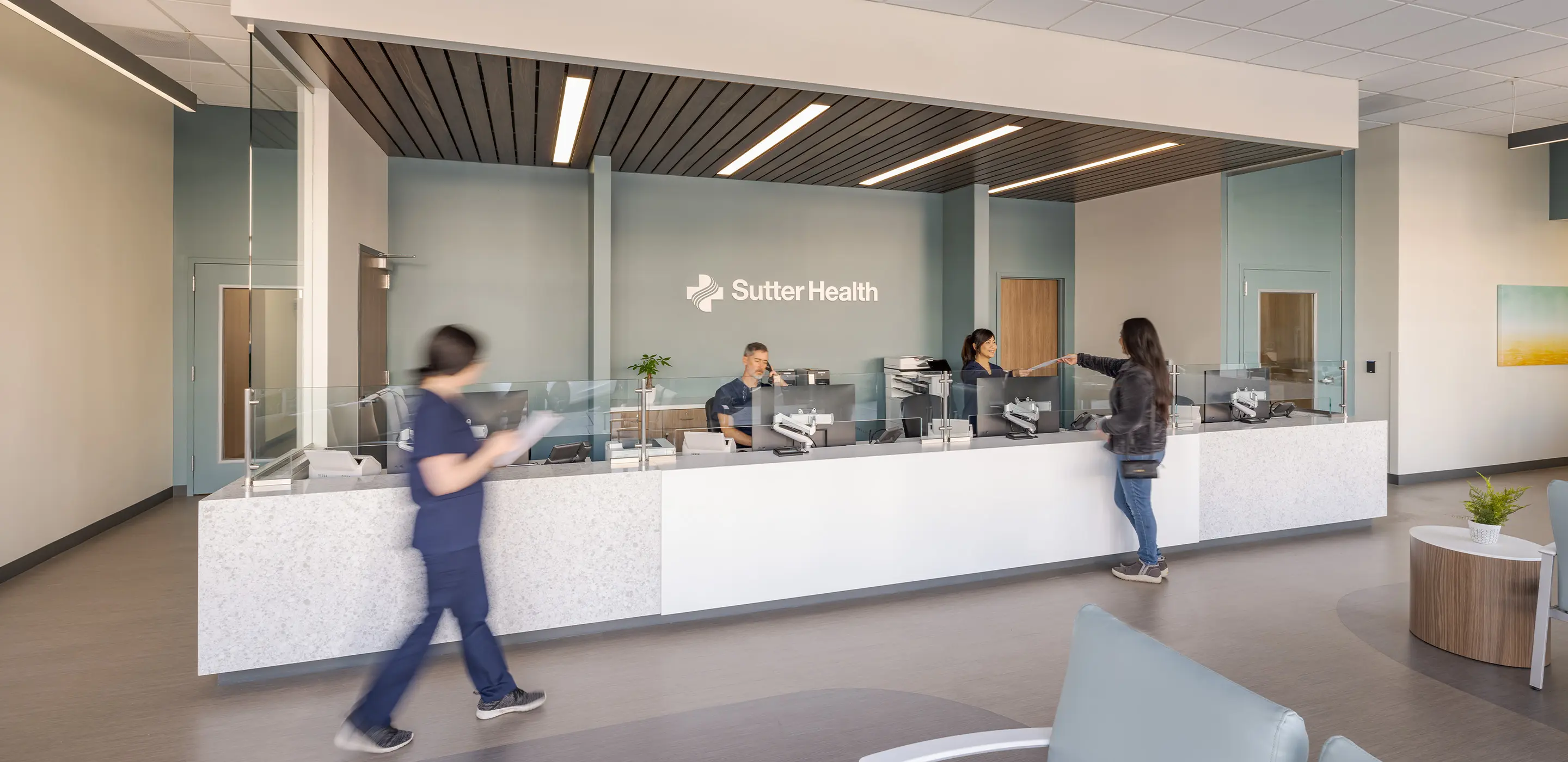 Reception desk inside a modern healthcare facility with staff and visitors.