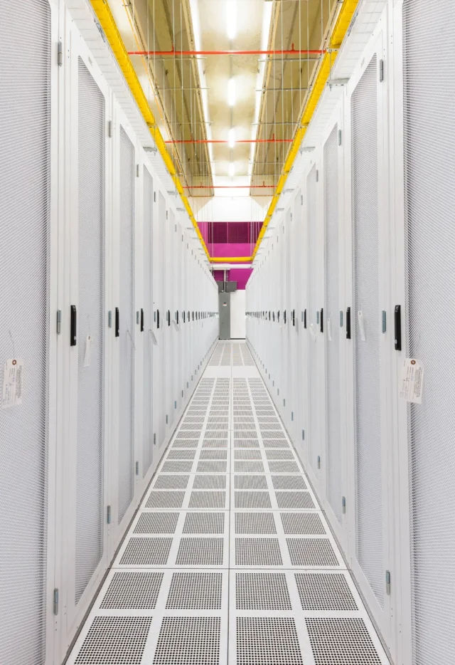 Bright, modern data center aisle with white server racks and overhead cabling, representing advanced technology infrastructure.