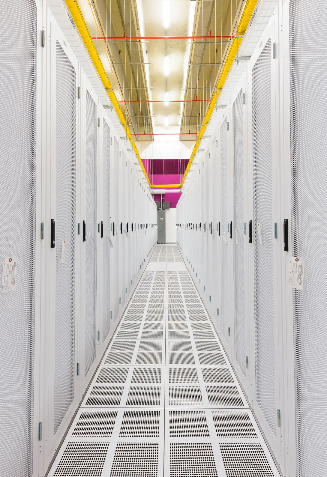 Bright, modern data center aisle with white server racks and overhead cabling, representing advanced technology infrastructure.