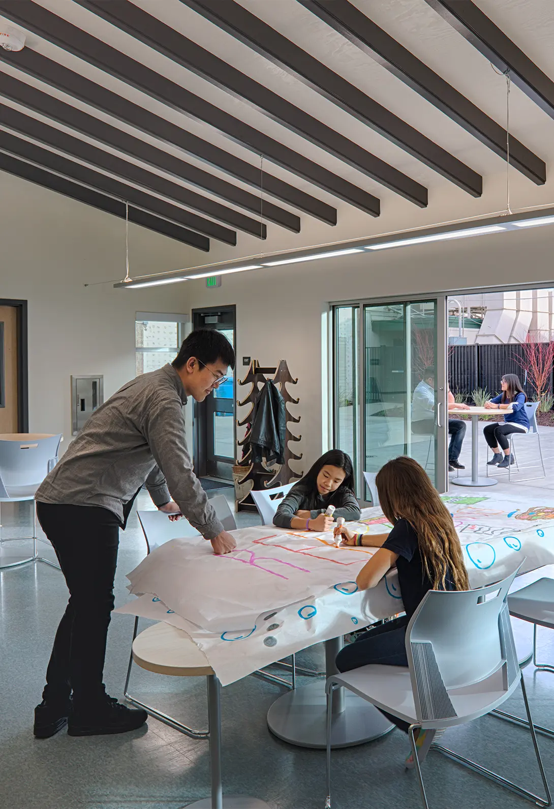 People collaborating on art project indoors, modern workplace, creative teamwork, natural light through open doors.