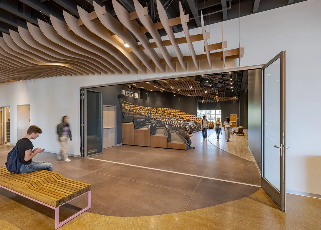 Modern auditorium with students and stylish ceiling design, showcasing spacious seating and open walkway.