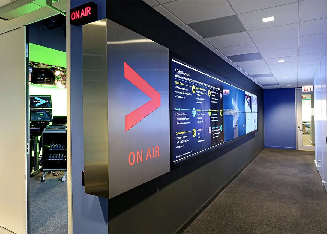 Modern office hallway with large digital screen and ON AIR sign, showcasing a tech-savvy workspace environment.
