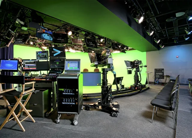 TV studio setup with green screen, cameras, monitors, and seating, ready for filming or live broadcast.