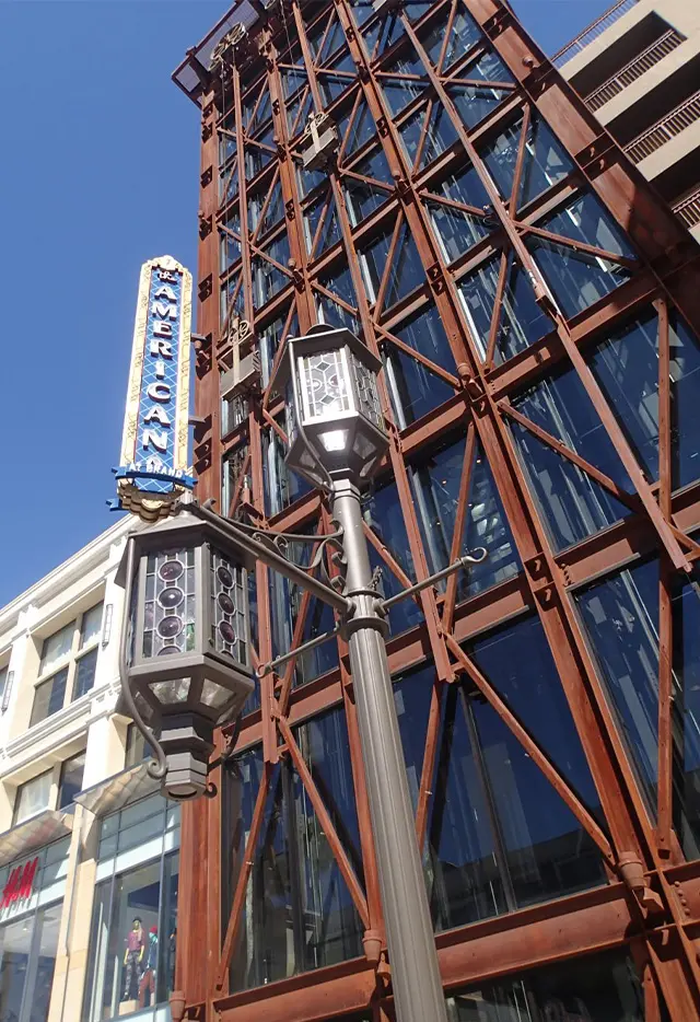 Historic building facade with vintage lantern, decorative metalwork, and blue sky background. American-brand sign visible.