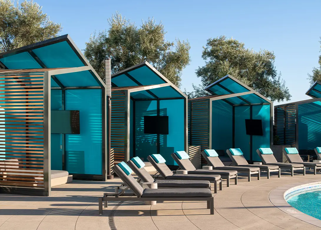 Poolside cabanas with lounge chairs under blue skies, offering relaxation and comfort.