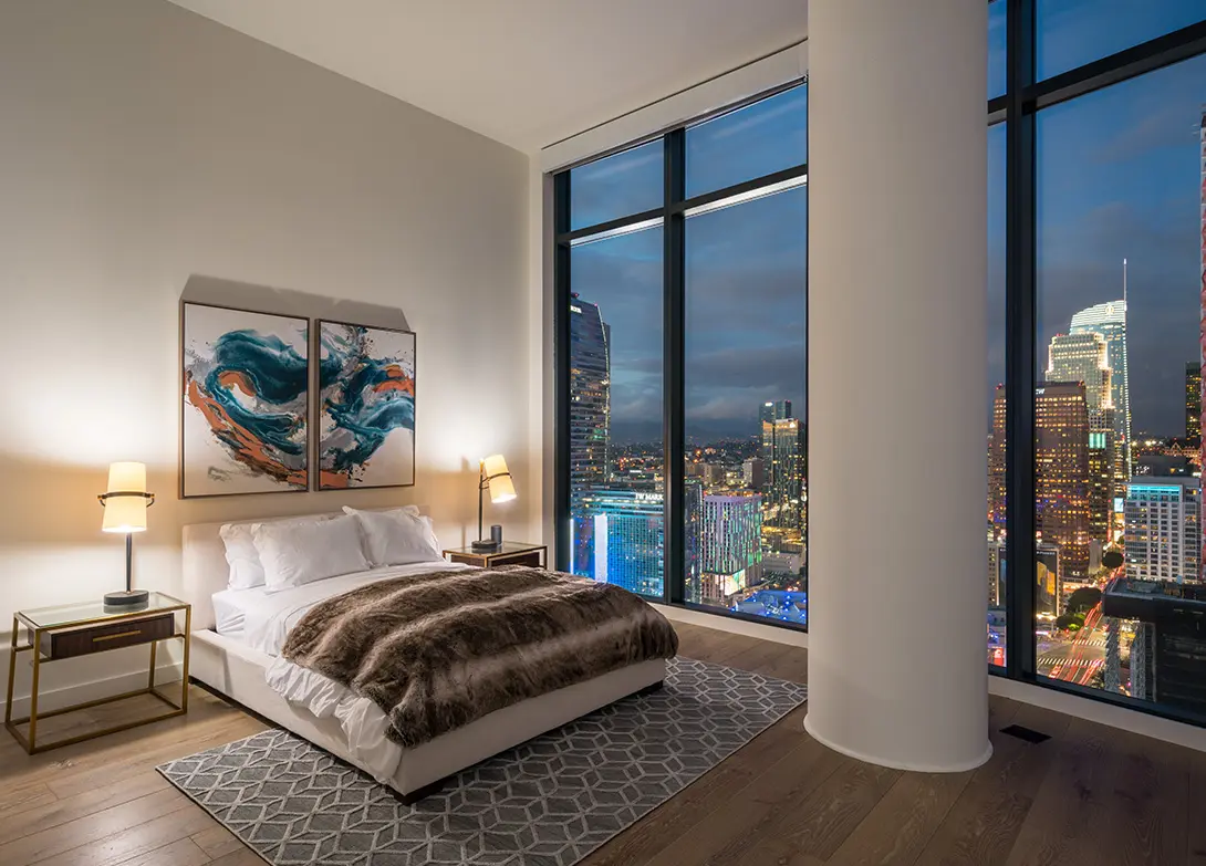 Luxury bedroom with city skyline view, modern decor, and floor-to-ceiling windows.