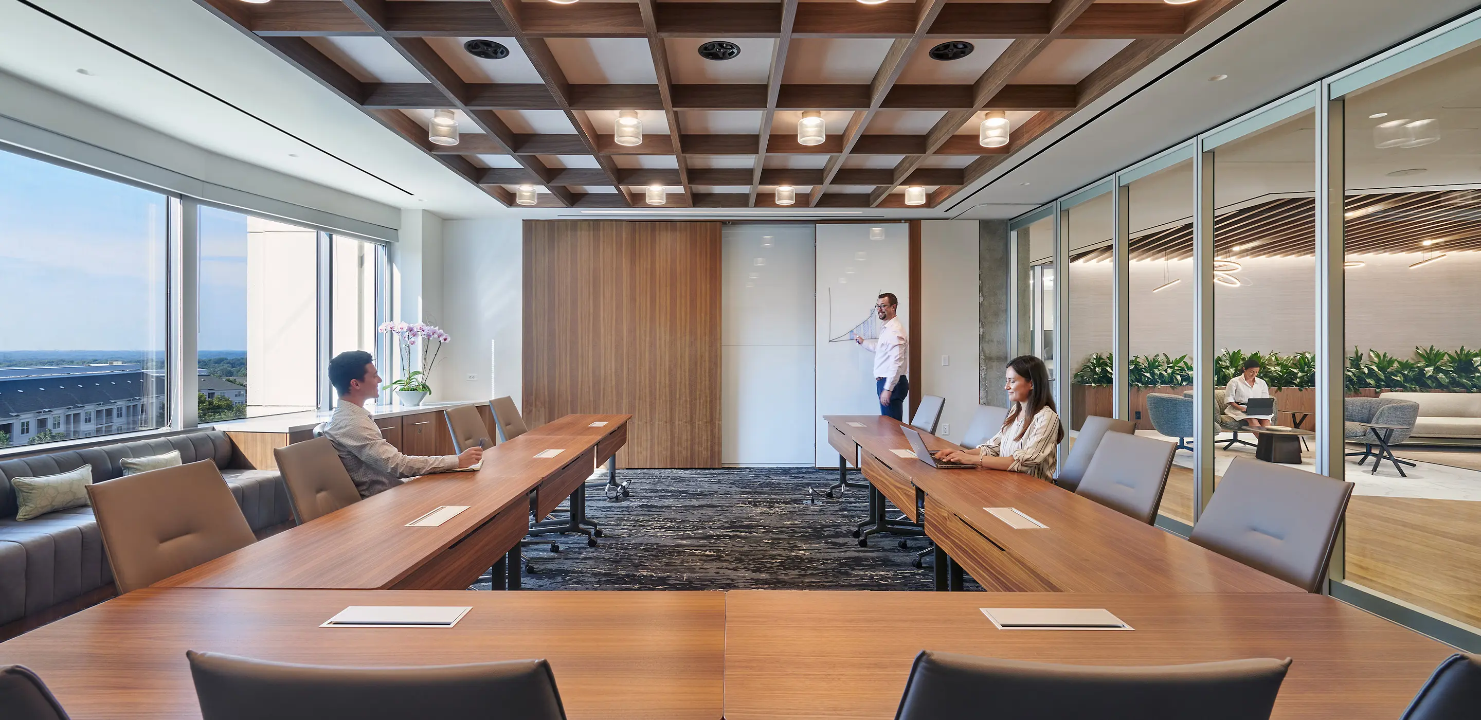 Modern conference room with people working, ample natural light, and a professional ambiance.