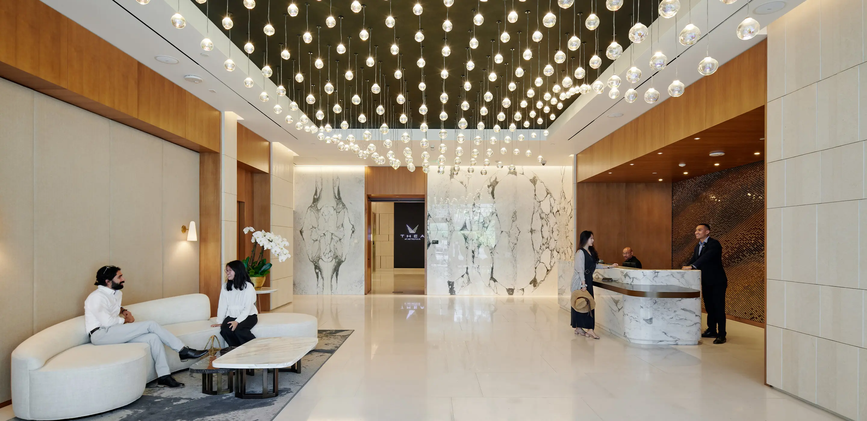 Luxurious hotel lobby with elegant marble decor, modern lighting, and guests interacting at the reception desk.