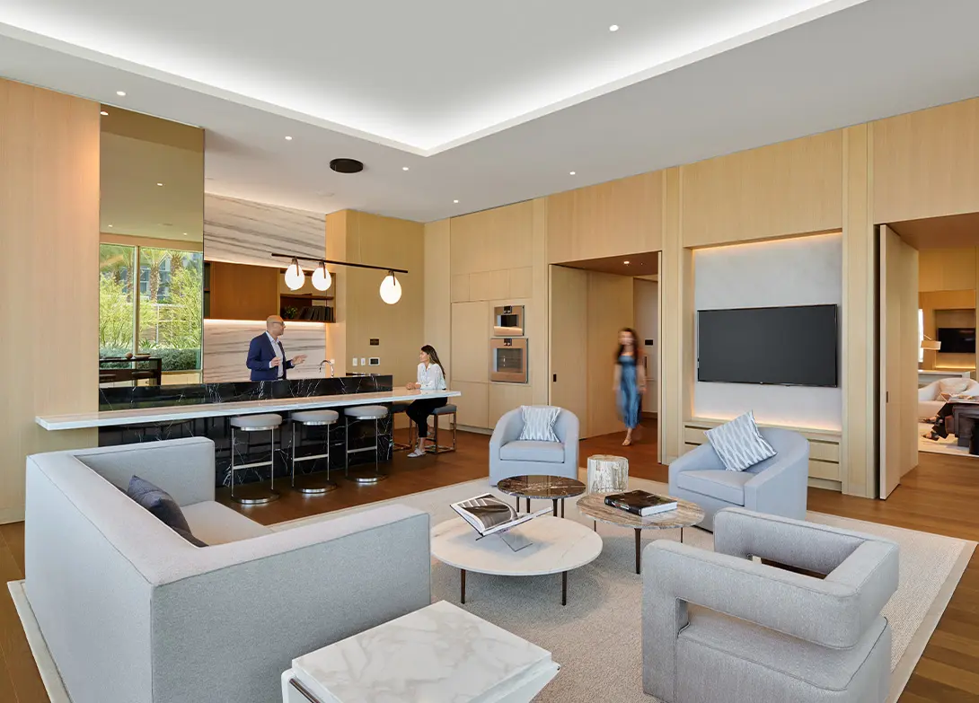 Modern open-concept living room with sleek furniture, kitchen bar seating, and stylish wooden accents.