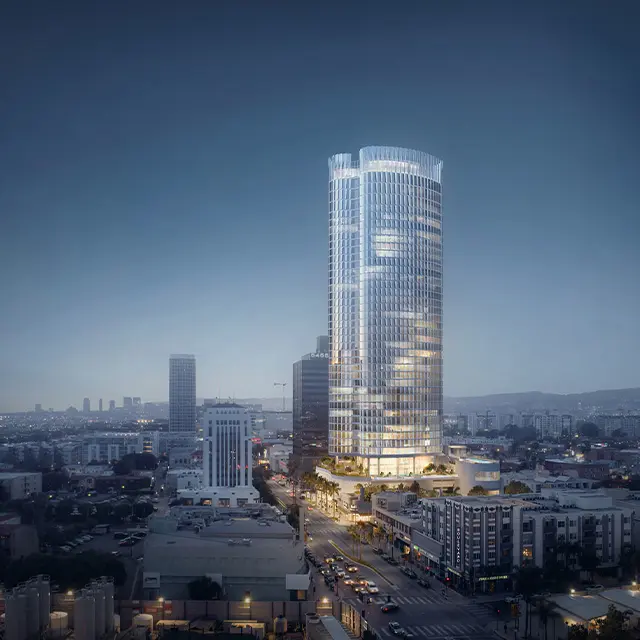 Tall modern skyscraper illuminated at night, overlooking cityscape with glowing streets and surrounding buildings.