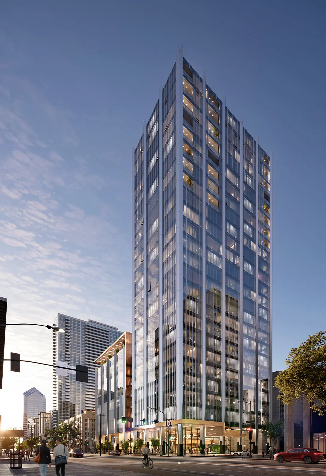 Modern skyscraper in city skyline at dusk with street activity and a clear sky in the background.