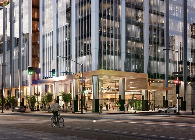 Modern urban street scene with cyclist, tall glass buildings, and illuminated storefronts at dusk.