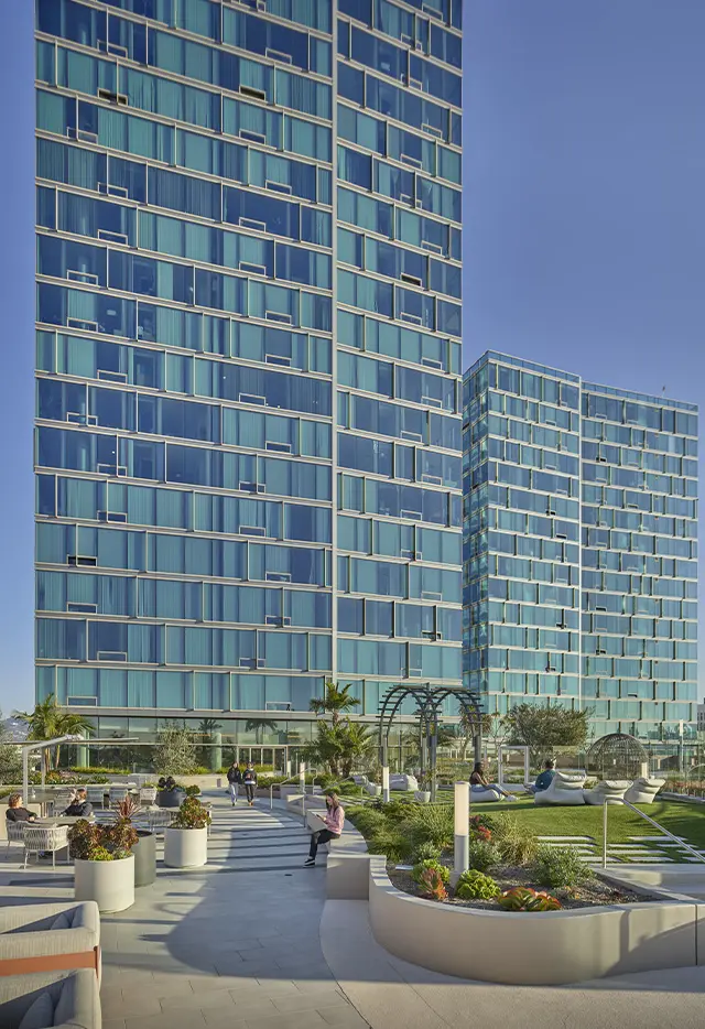 Modern high-rise buildings with glass facades and landscaped terrace featuring seating areas.