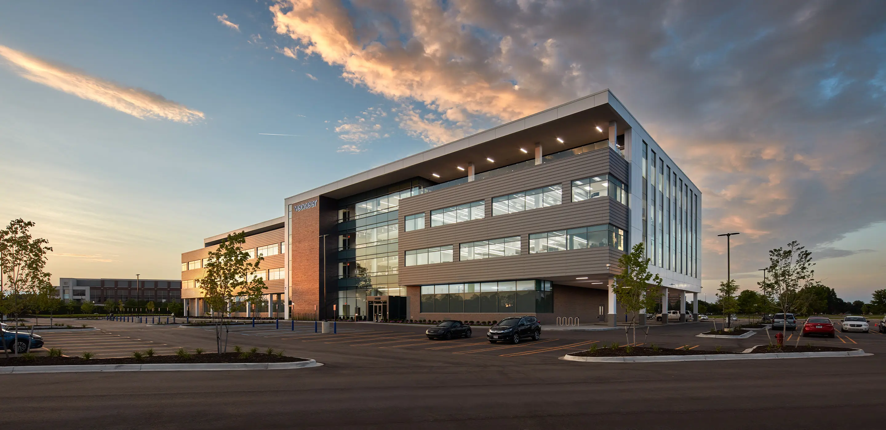 Modern office building at sunset with ample parking and clear skies.