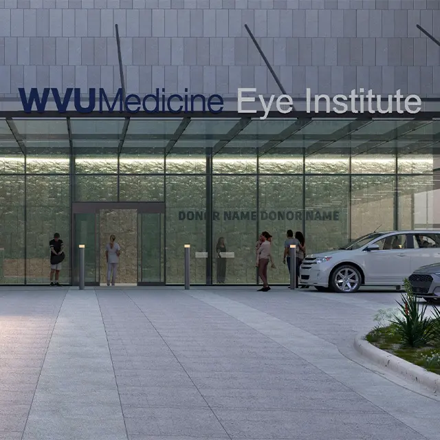 WVU Medicine Eye Institute entrance with people and parked car, glass facade, evening lighting.