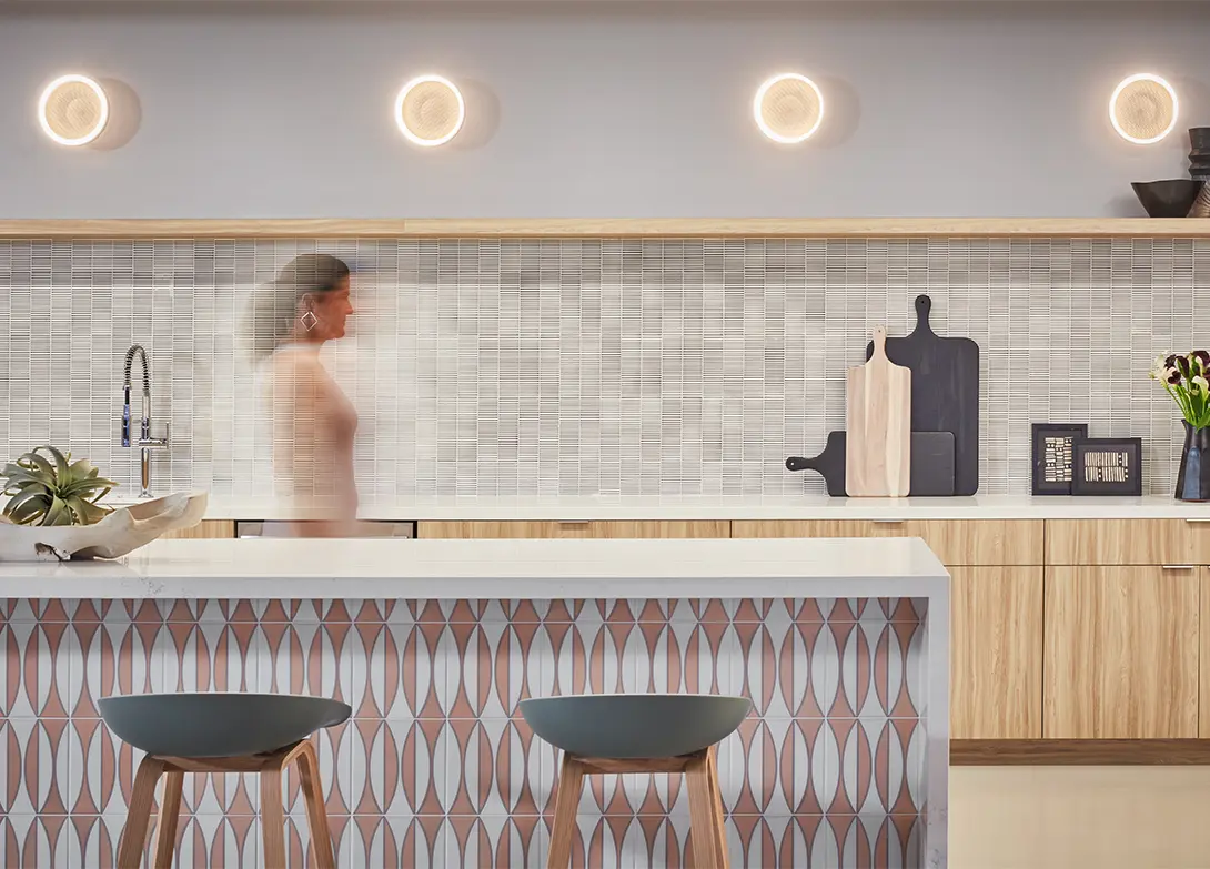 Modern kitchen with stylish lighting, patterned tiles, and a blurred figure in motion.