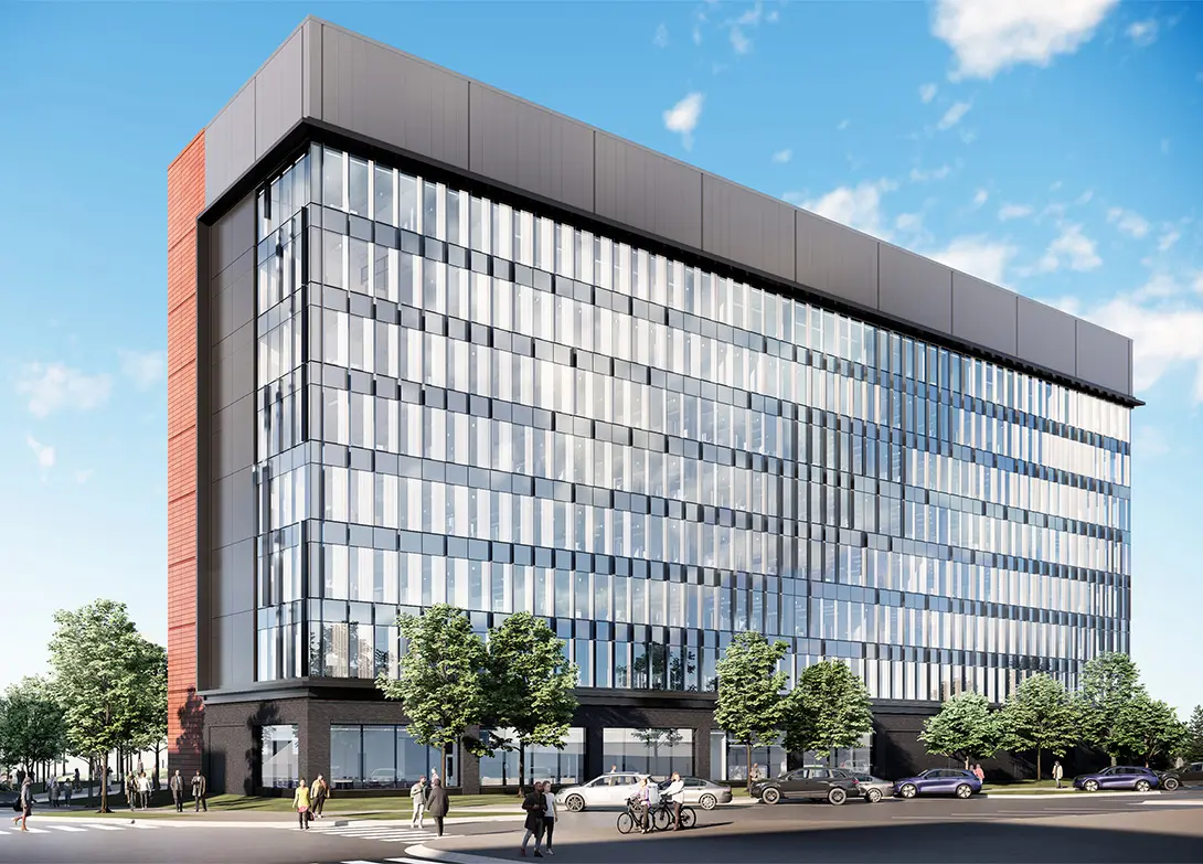 Modern office building with glass facade in urban setting, featuring trees and cars on a sunny day.