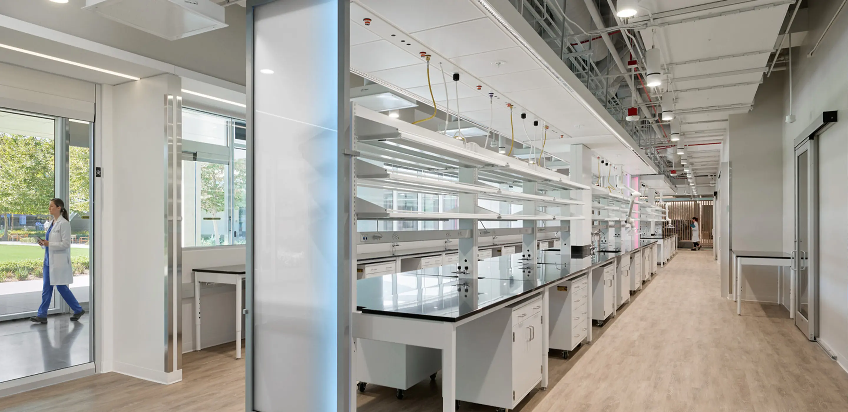 Modern laboratory interior with white benches, storage cabinets, and overhead lighting.
