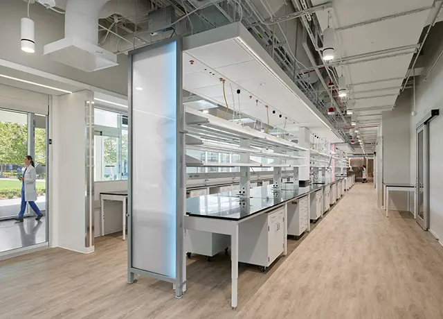 Modern laboratory interior with long rows of workbenches and bright lighting for scientific research and development.
