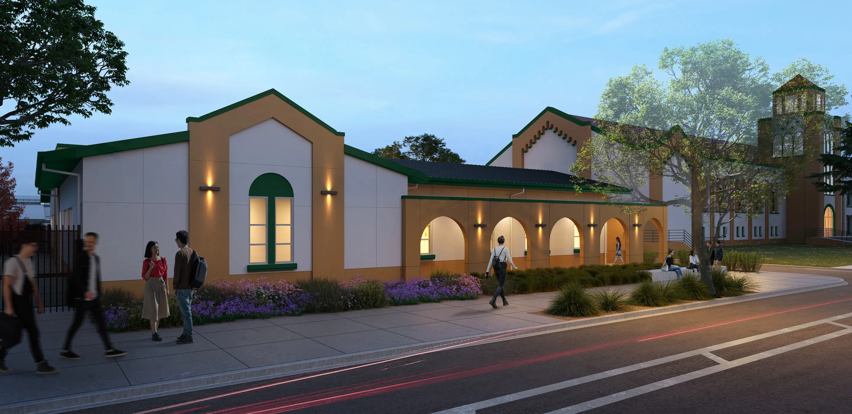 Modern building exterior at dusk with people walking and talking near landscaped sidewalk.