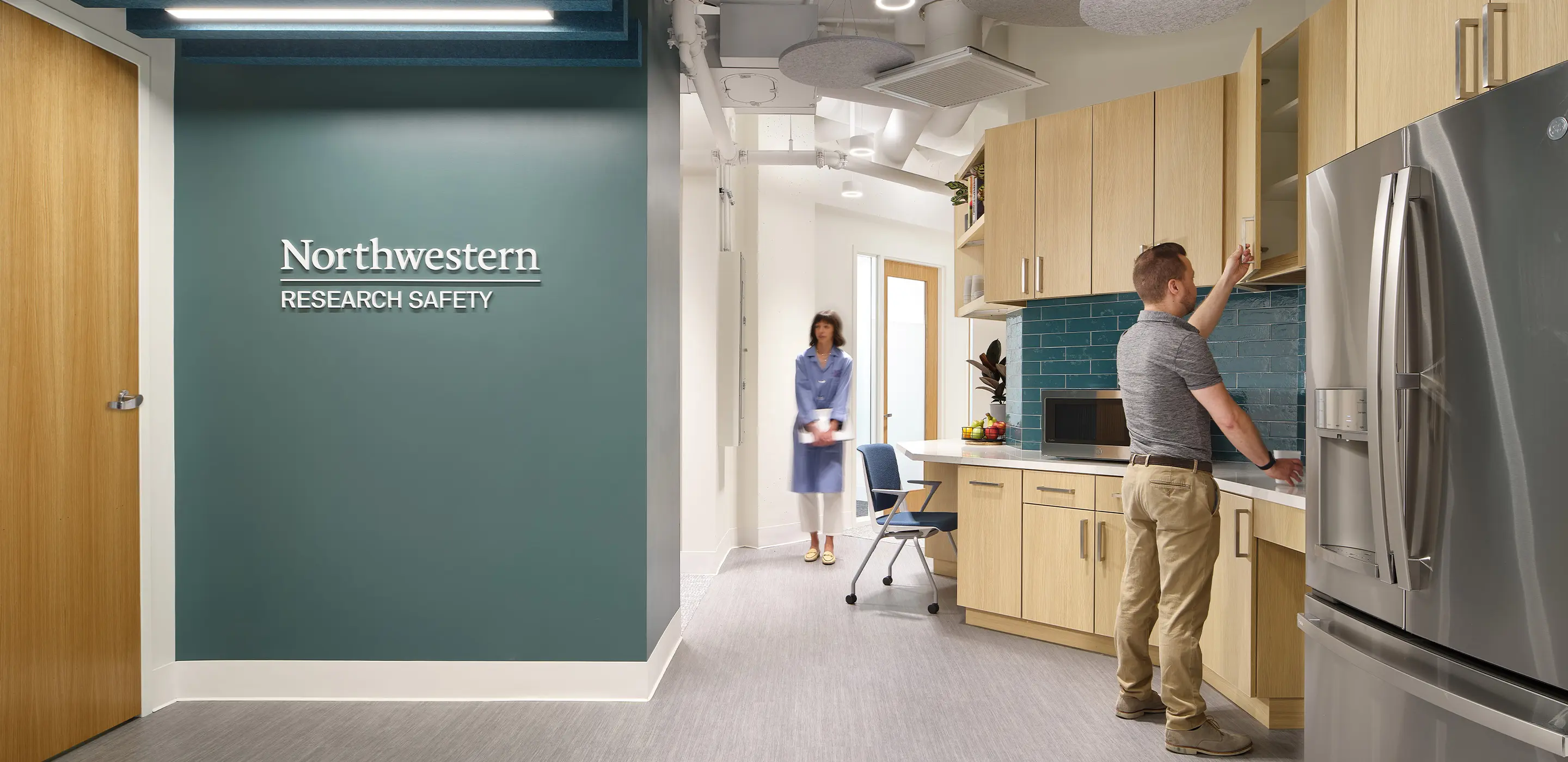 Modern Northwestern research lab kitchen with staff, wooden cabinets, and a sleek refrigerator.