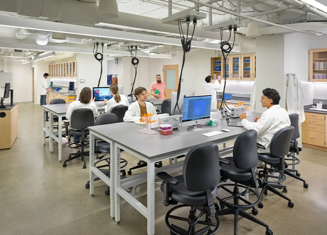 Modern research lab with scientists in white coats working at computers and conducting experiments.