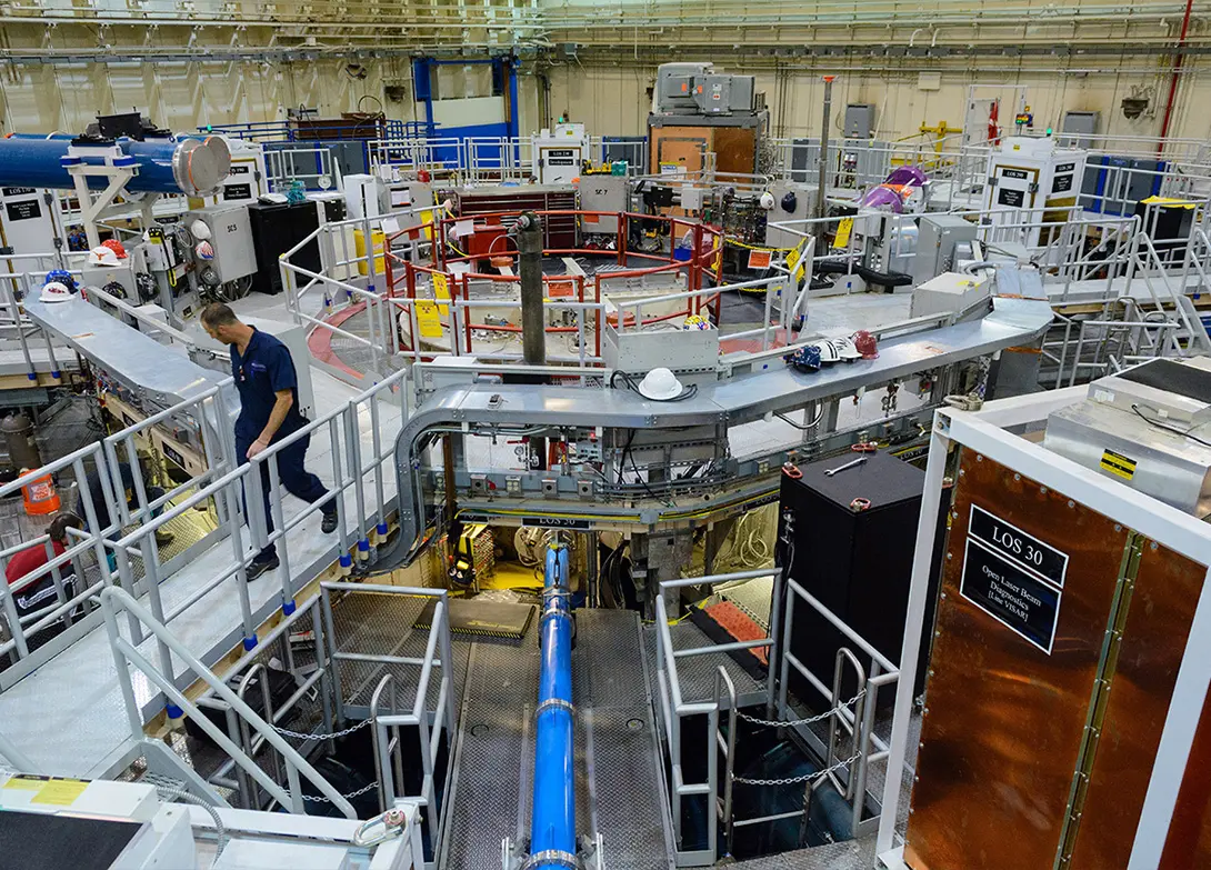 Industrial laboratory with advanced equipment and a worker conducting maintenance amidst complex machinery.