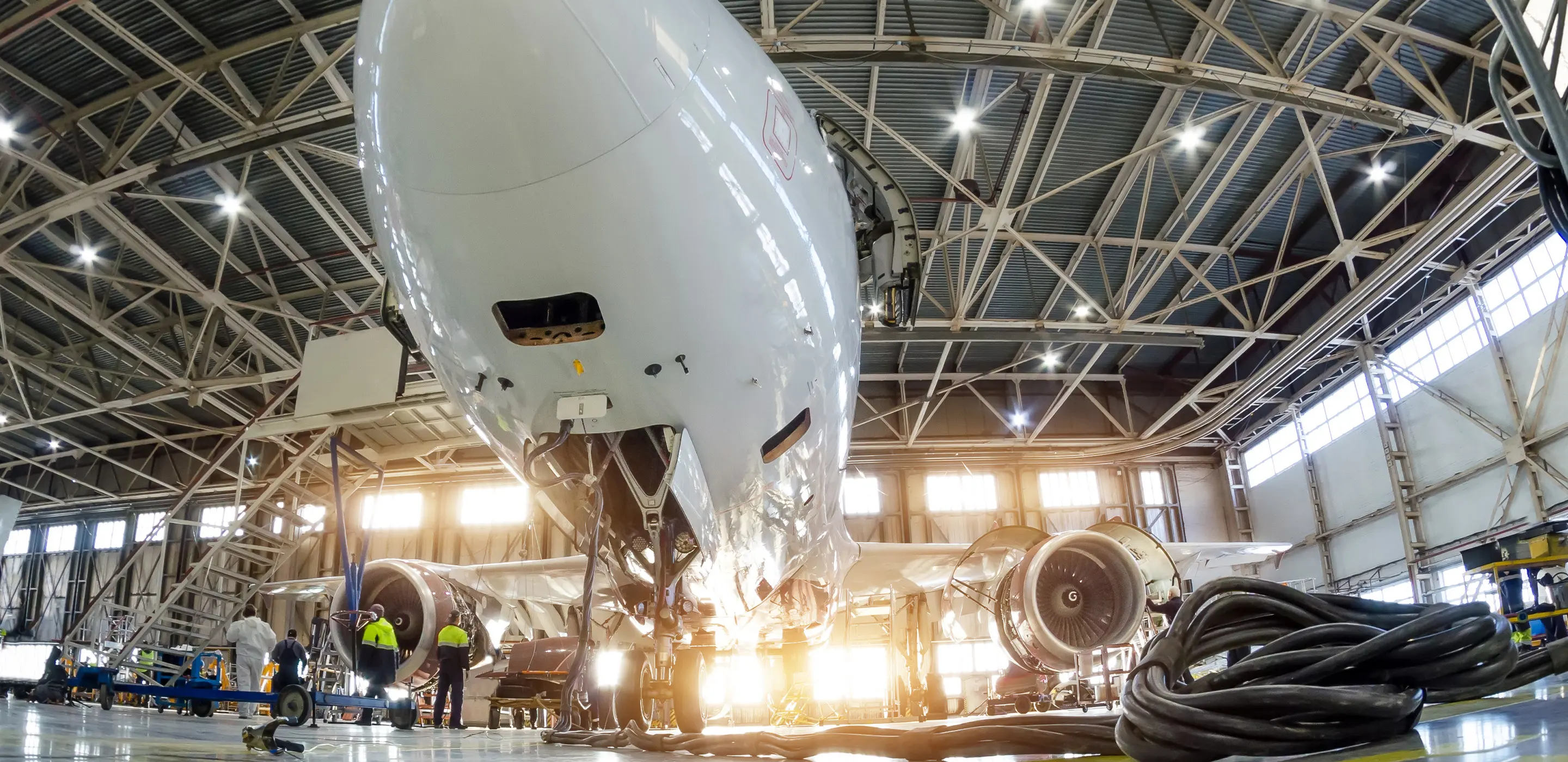 Airplane in maintenance hangar with engineers working on engines.