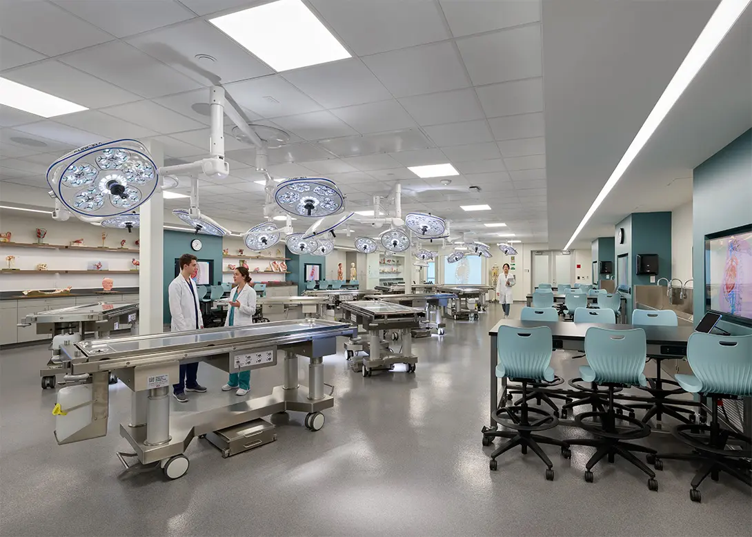 Modern medical lab with surgical equipment, students in white coats, and anatomical models on display.