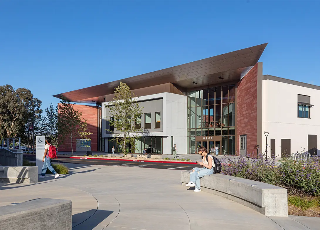 Modern campus building with students outside under a clear blue sky.