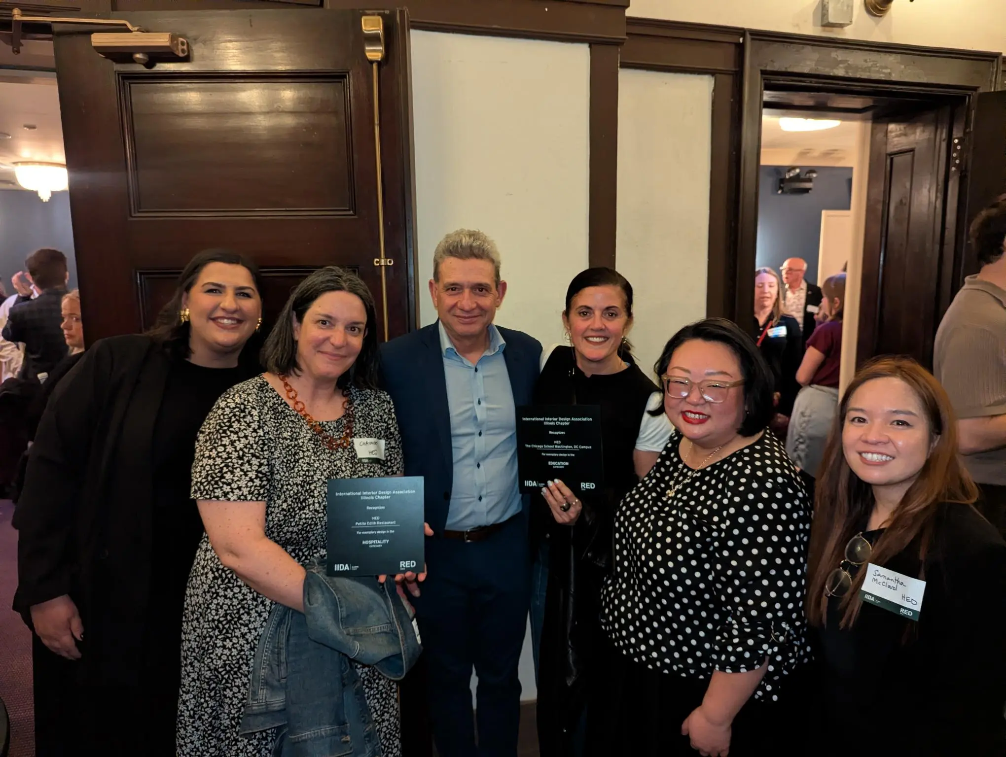 Group of people at an awards event holding plaques, standing together and smiling.