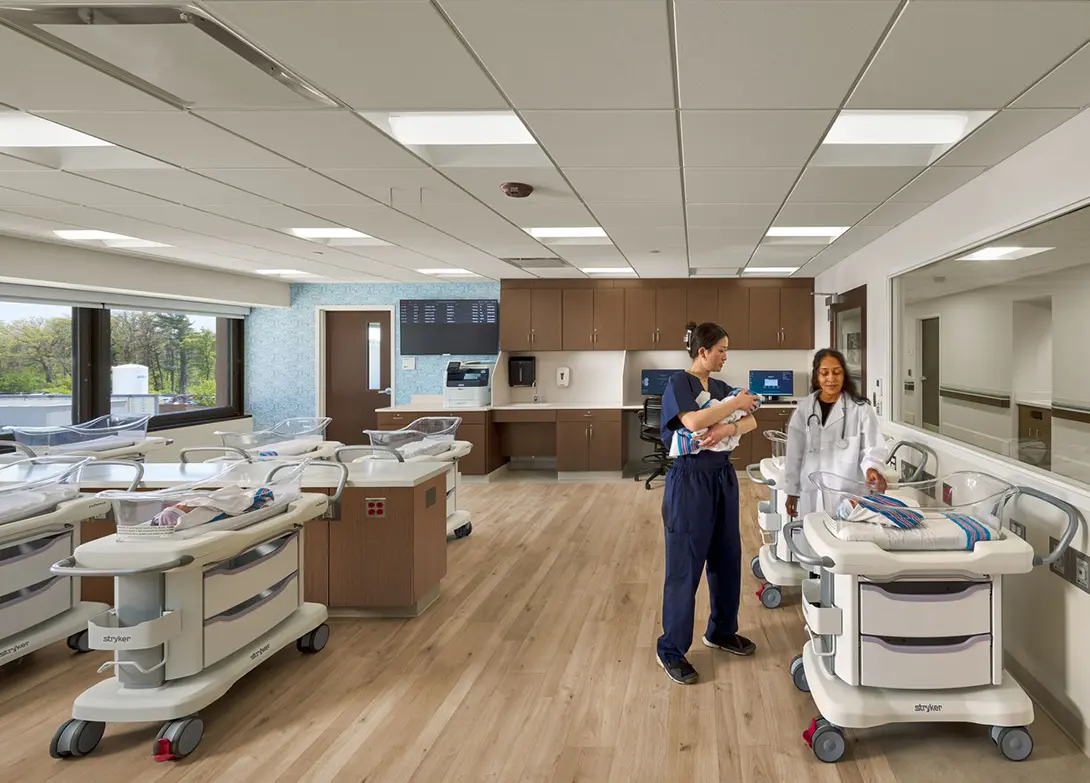 Modern hospital nursery with medical staff caring for newborns in bassinets. Bright, clean, and welcoming environment.