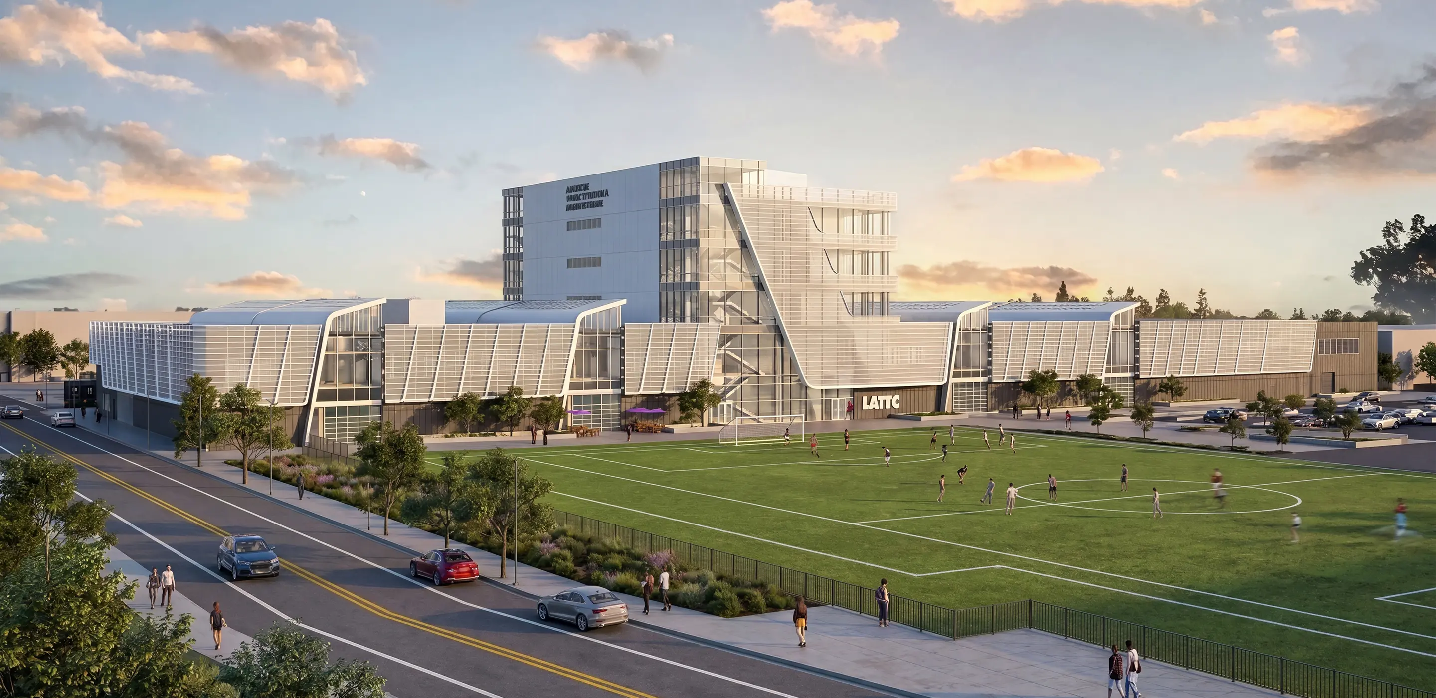 Modern architectural building with glass facade, sports field, and people walking nearby under a vibrant sky.