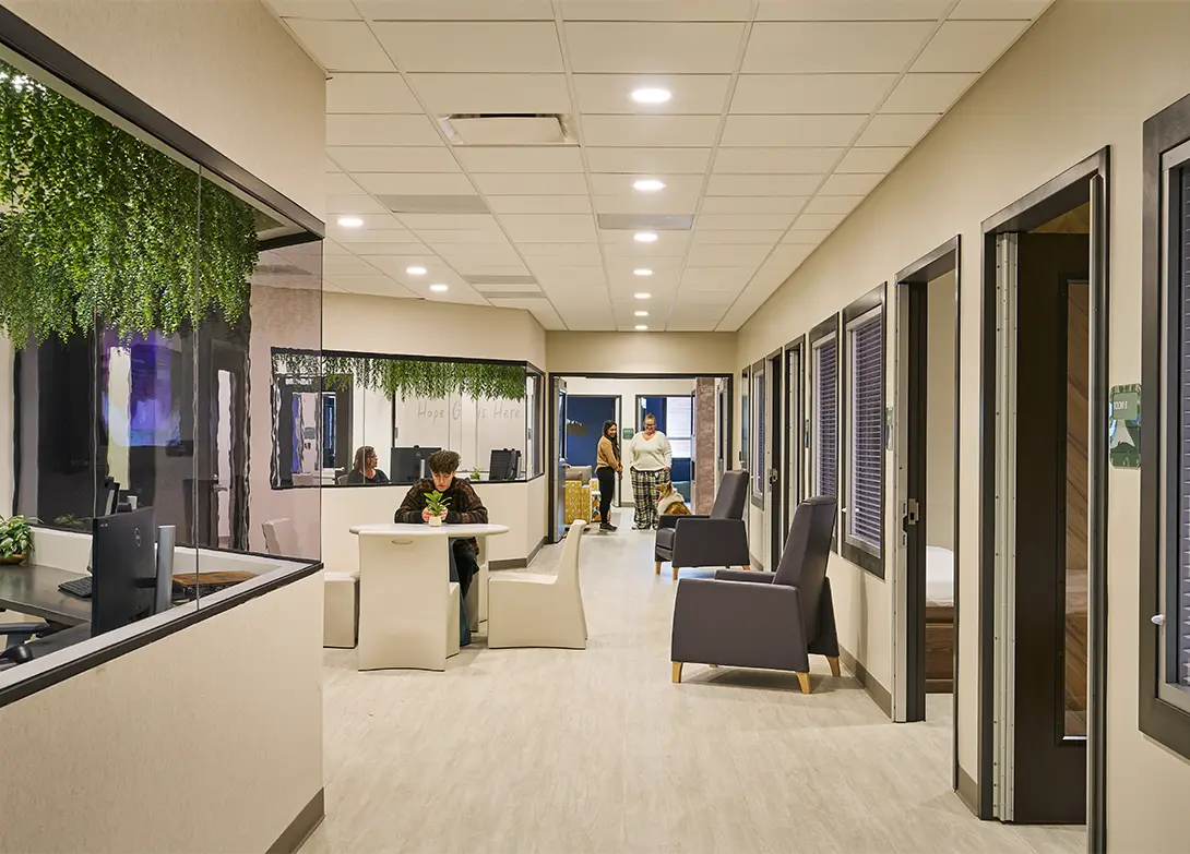Modern office lobby with seating, plants, and people meeting in a bright, welcoming environment.